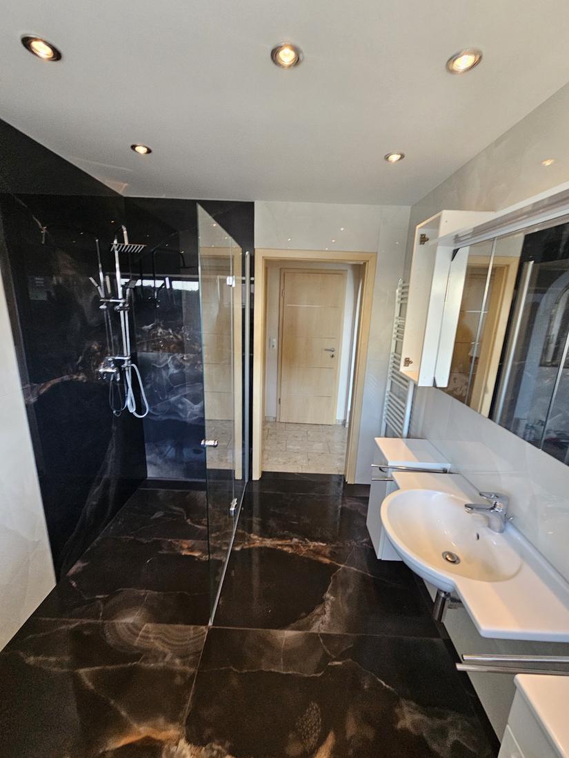 Bad mit großformatigen Fliesen in schwarzer Marmoroptik und Walk-in-Dusche