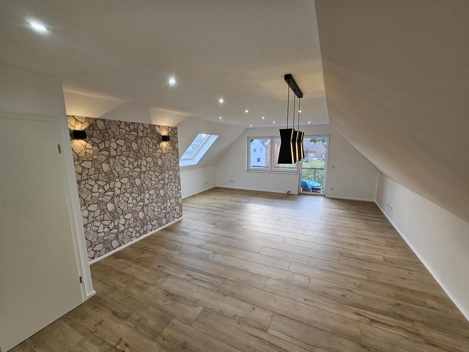 Wohnraum im Dachgeschoss mit Boden in Holzoptik und Steinwand